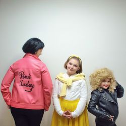 Portrait of happy friends standing against wall