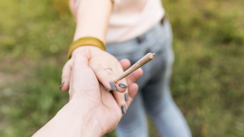 Close-up of couple smoking marijuana joint outdoors