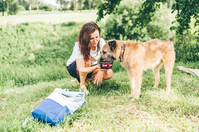 Portrait of young woman with dog on field