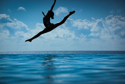 Man jumping in sea against sky