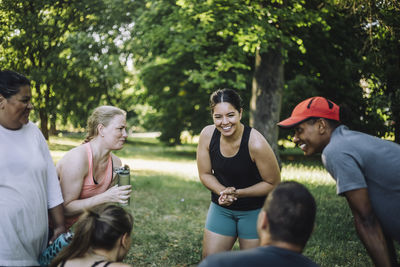 Happy woman talking with male and female friends after working out at park