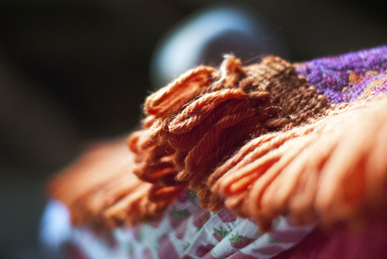 selective focus, close-up, indoors, art and craft, textile, wool, one person, craft, multi colored, real people, focus on foreground, creativity, pattern, human body part, thread, knitting, material, food, knitting needle, warm clothing