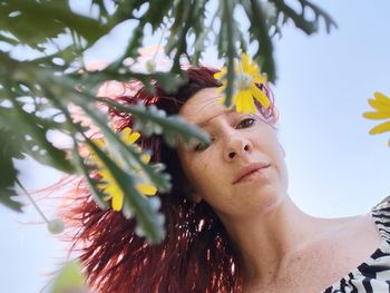 Close-up portrait of redhead woman by flowering plant