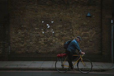 Man riding bicycle on street against wall