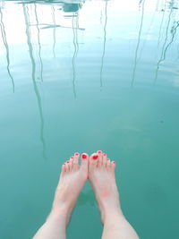 Low section of woman sitting by lake