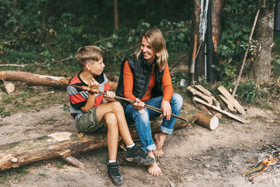 A mother and her teenage son are sitting on a tree in campsites 