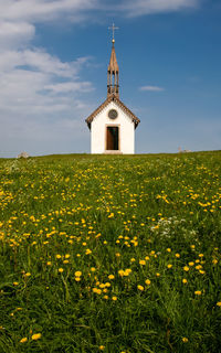 View of little chapel on field against cloudy sky