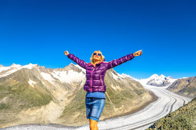 Full length of man standing on mountain against blue sky