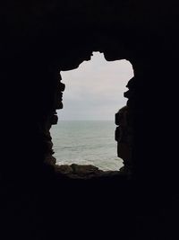 Scenic view of sea against sky seen through cave