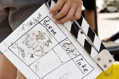 Midsection of man holding film slate while standing outdoors