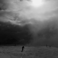 People skiing on snow against cloudy sky