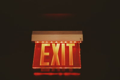 Low angle view of illuminated sign against black background