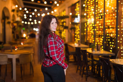 Smiling woman standing against illuminated lights at night