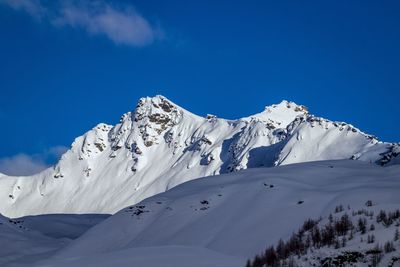 Low angle view of snowcapped mountains against blue sky