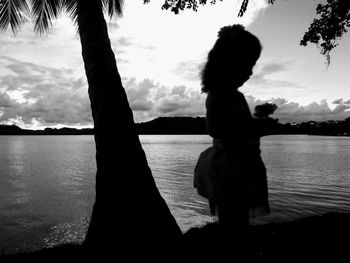 Silhouette woman standing by lake against sky