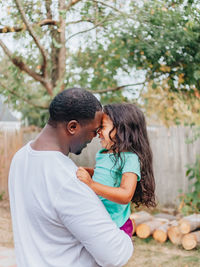 Black or african american father in white shirt in the back yard playing with mixed race daughter