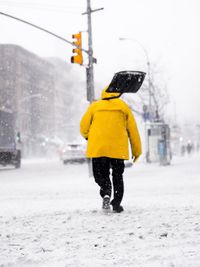 Rear view of man walking on road during winter