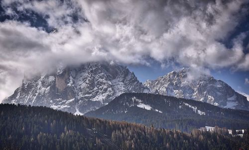 Scenic view of snow covered mountains against cloudy sky