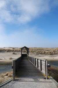 View of wooden footbridge against sky