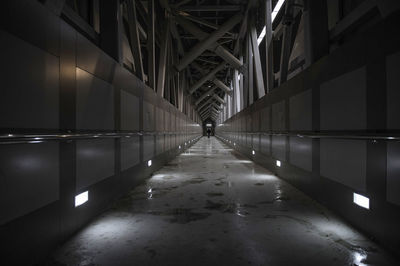 Rear view of person walking in illuminated corridor