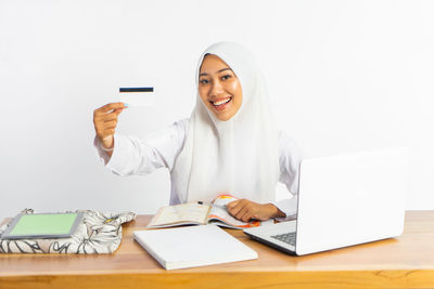 Young woman using mobile phone while sitting on table