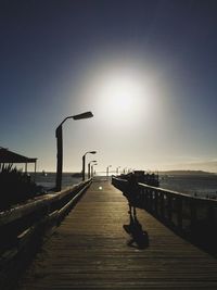 Pier over sea against clear sky during sunset