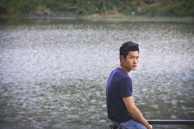 Side view of young man looking away in lake