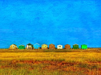 Houses on field against blue sky