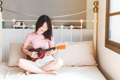 Young woman sitting on guitar at home