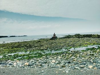 Man walking on beach against sky