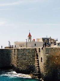 Built structure by sea against sky
