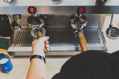 Cropped image of man using espresso maker at cafe