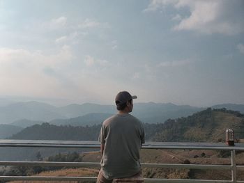 Rear view of man looking at mountains against sky