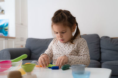 Cute girl playing with clay at home