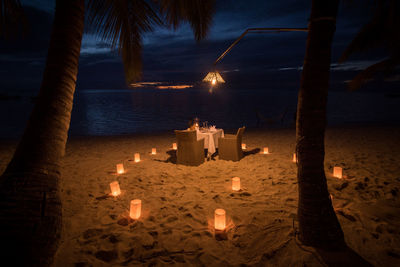 Illuminated beach against sky at night