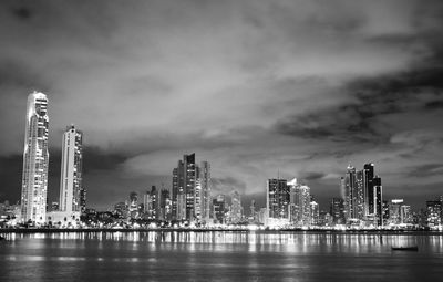 City at waterfront against cloudy sky