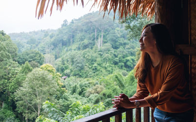 A female traveler standing on balcony and looking at a beautiful green mountain view