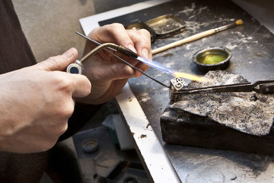 Cropped hands of person burning metal at workshop