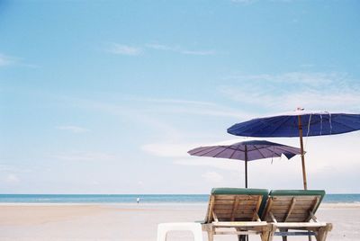 Chairs and parasols at beach against sky