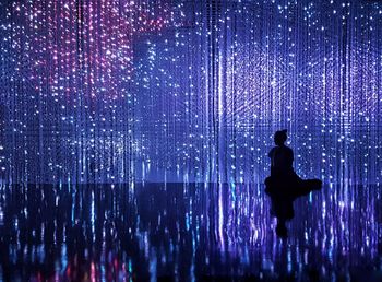 Rear view of silhouette woman sitting against illuminated decoration