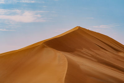 Low angle view of sand dunes against sky