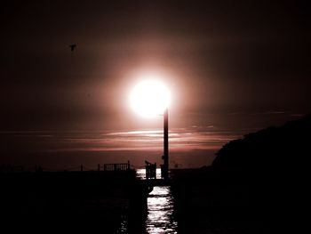 Silhouette of bridge over sea during sunset