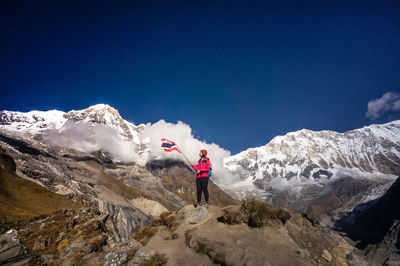 Woman with flag standing on mountain against sky