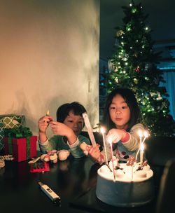 Full length of happy girl holding illuminated christmas tree at home