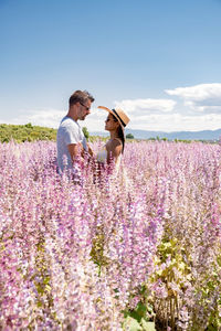 Rear view of people on flowering field against sky