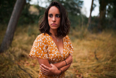 Outdoor portrait of a beautiful brunette woman wearing a dress in the forest