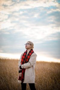 Young woman standing on field against sky