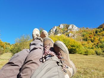 Low section of man and woman against clear blue sky