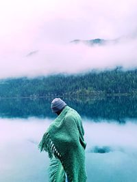 Person in lake against sky during winter