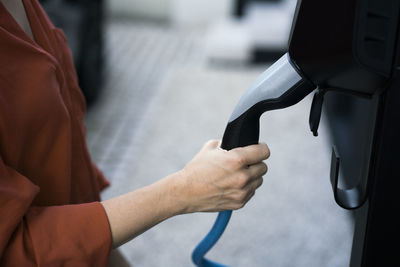 Hand of woman holding electric car charger plug
